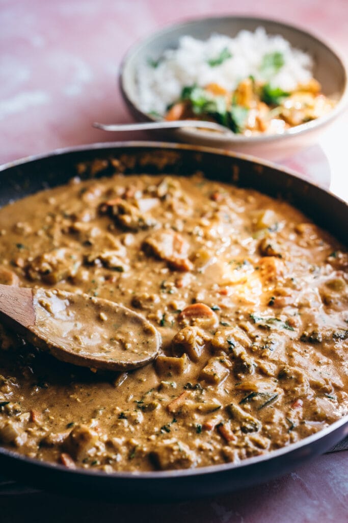 a side view of a skillet filled to the brim with creamy looking vegetable korma