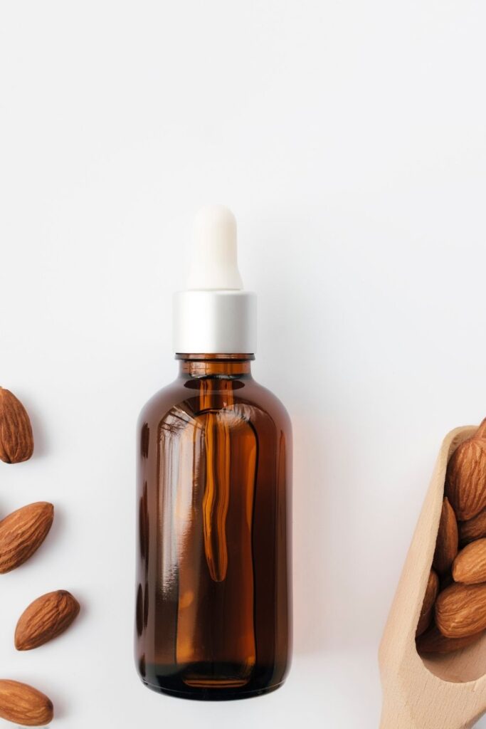 an amber glass bottle filled with almond extract surround by scattered raw almonds