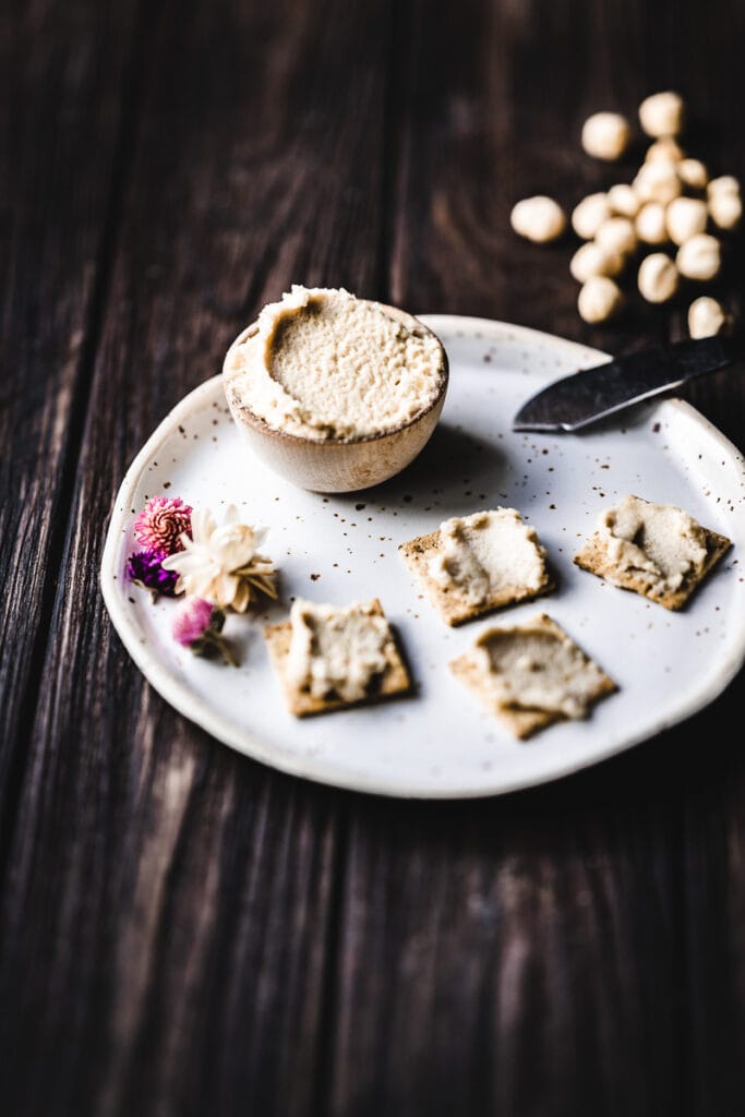 crackers spread with vegan cream hazelnut cream cheese rest on white ceramic plate