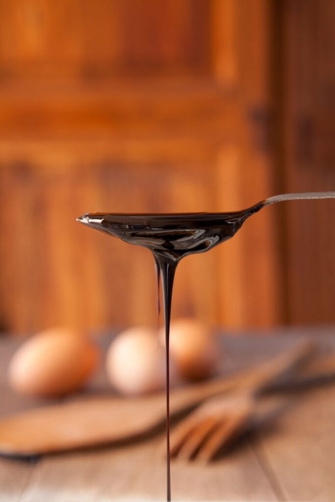a silve spoon dripping with dark brown molasses