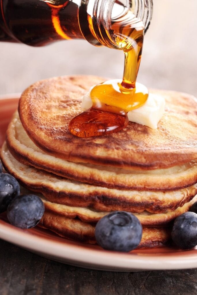  Ahornsirup wird auf einen Stapel Pfannkuchen geträufelt, um Ahornsirup zu ersetzen