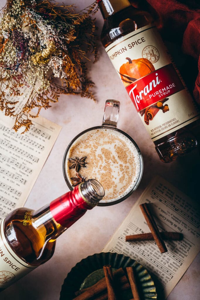 a bottle of torani pumpkin spice syrup being poured into a mug of pumpkin spice steamer