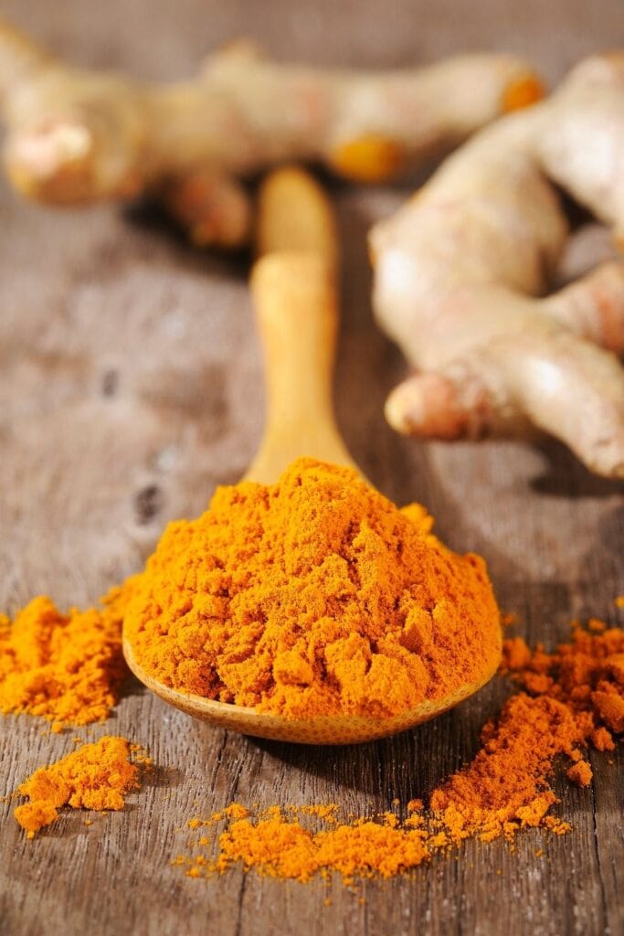 a wooden spoon filled with vibrant ground turmeric powder