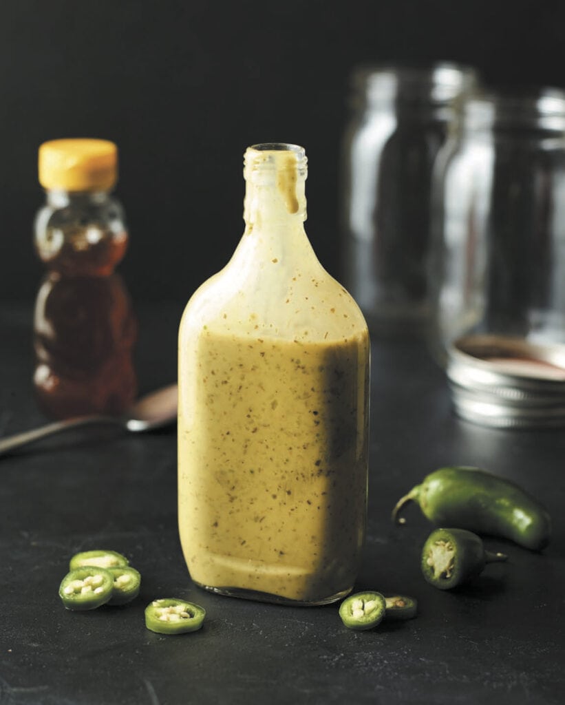 a clear jar filled with fermented jalapeno hot sauce