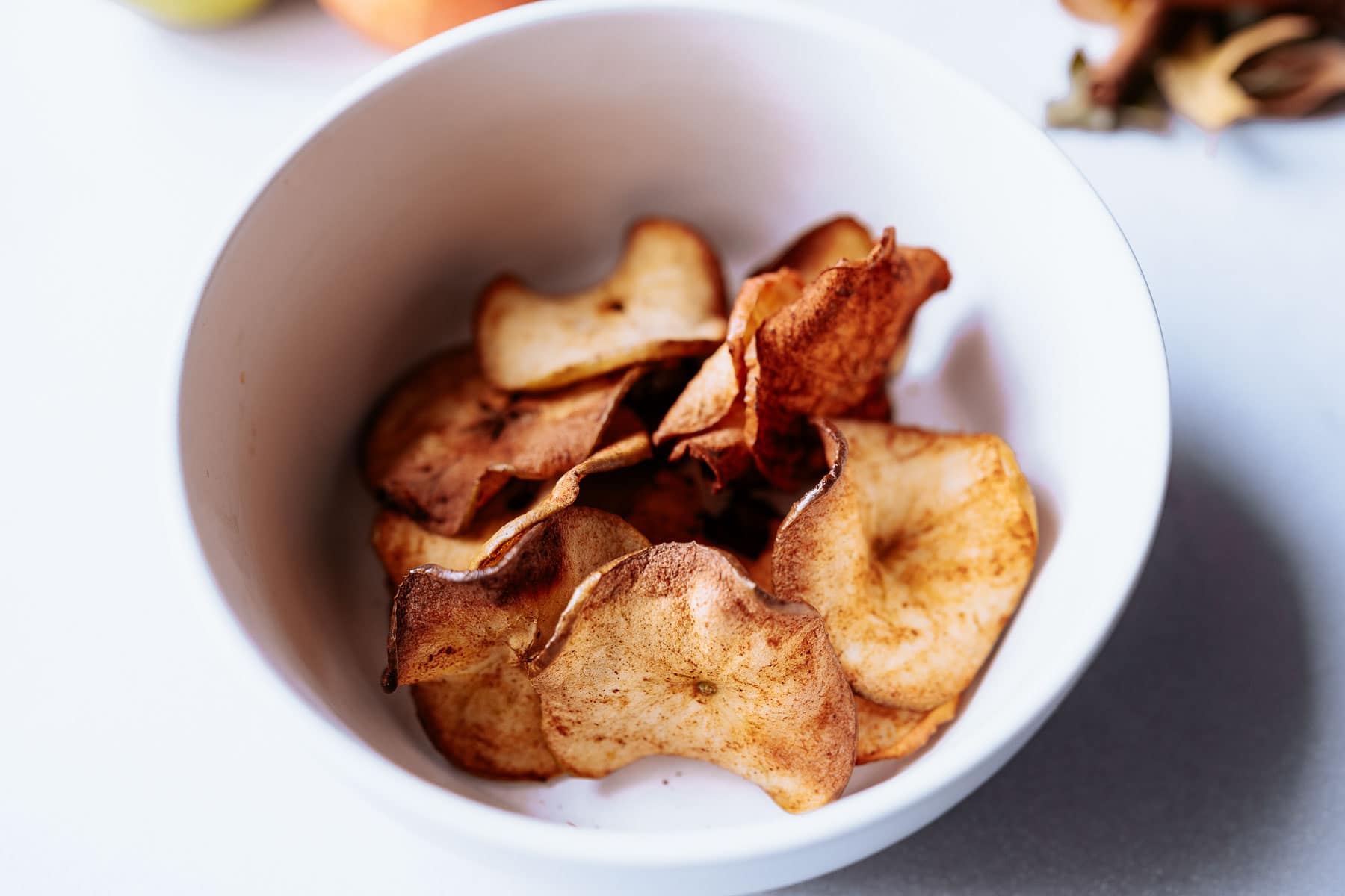 a white bowl filled with homemade air fryer apple chips