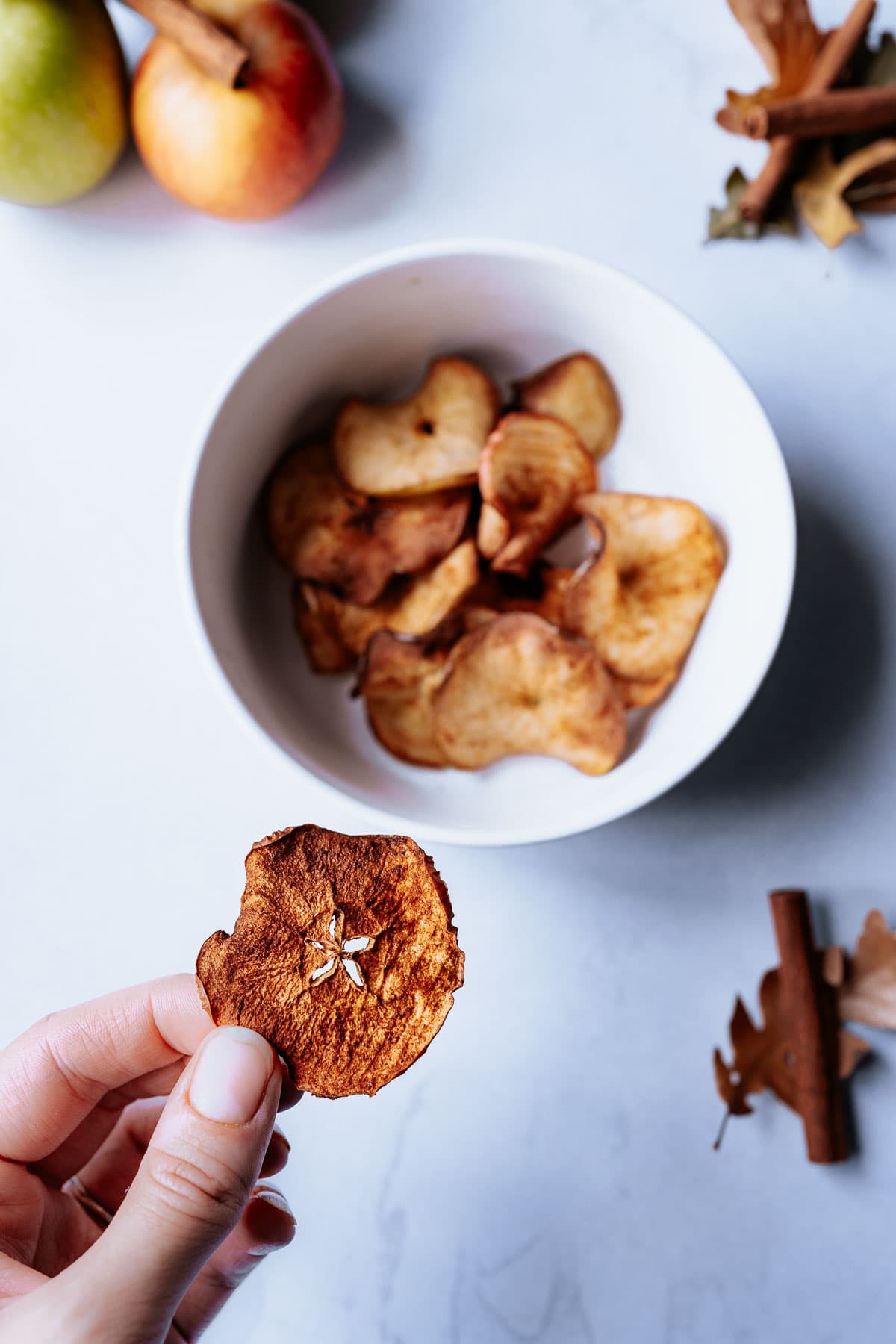 a hand holding an air fried apple chip