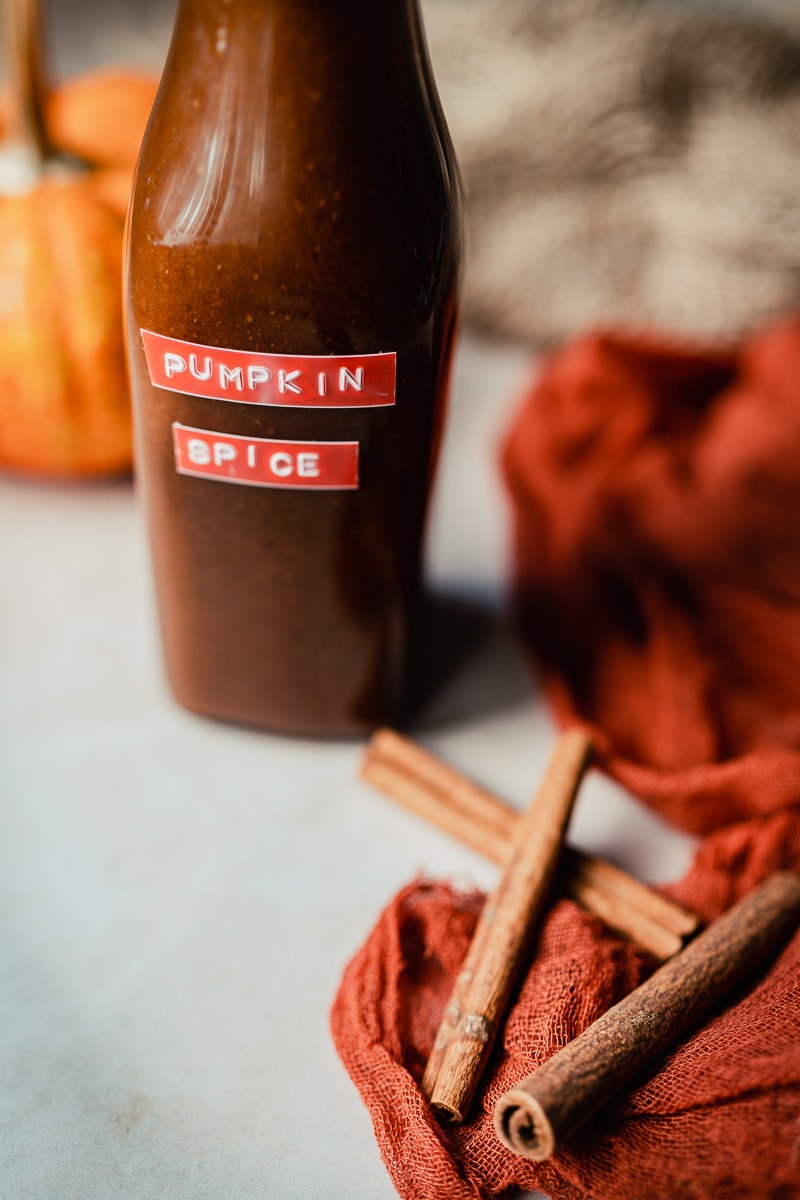 a clear swing top bottle of homemade vegan pumpkin spice syrup for a latte and more