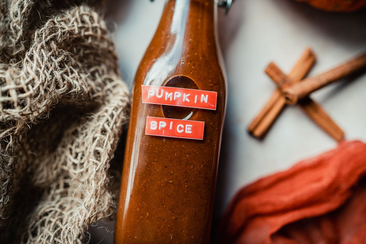 a swing top bottle filled with homemade pumpkin spice syrup and labeled with an orange label that says pumpkin spice