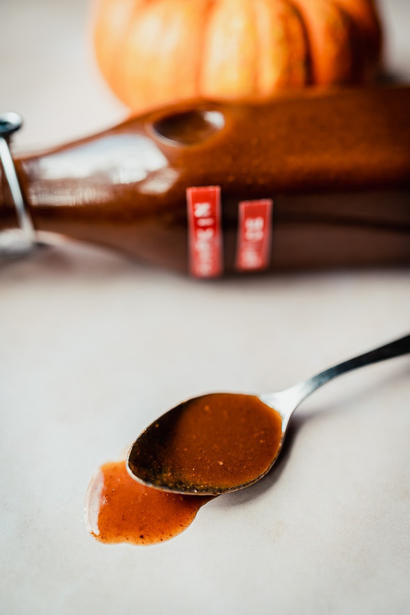 a small silver spoon spilling over with orange pumpkin spice syrup