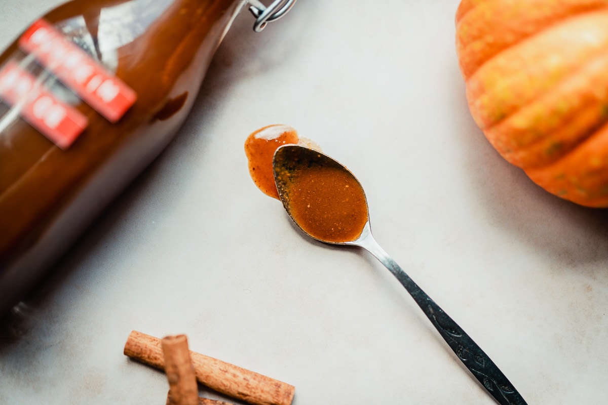 a silver spoon drizzling freshly homemade pumpkin spice syrup