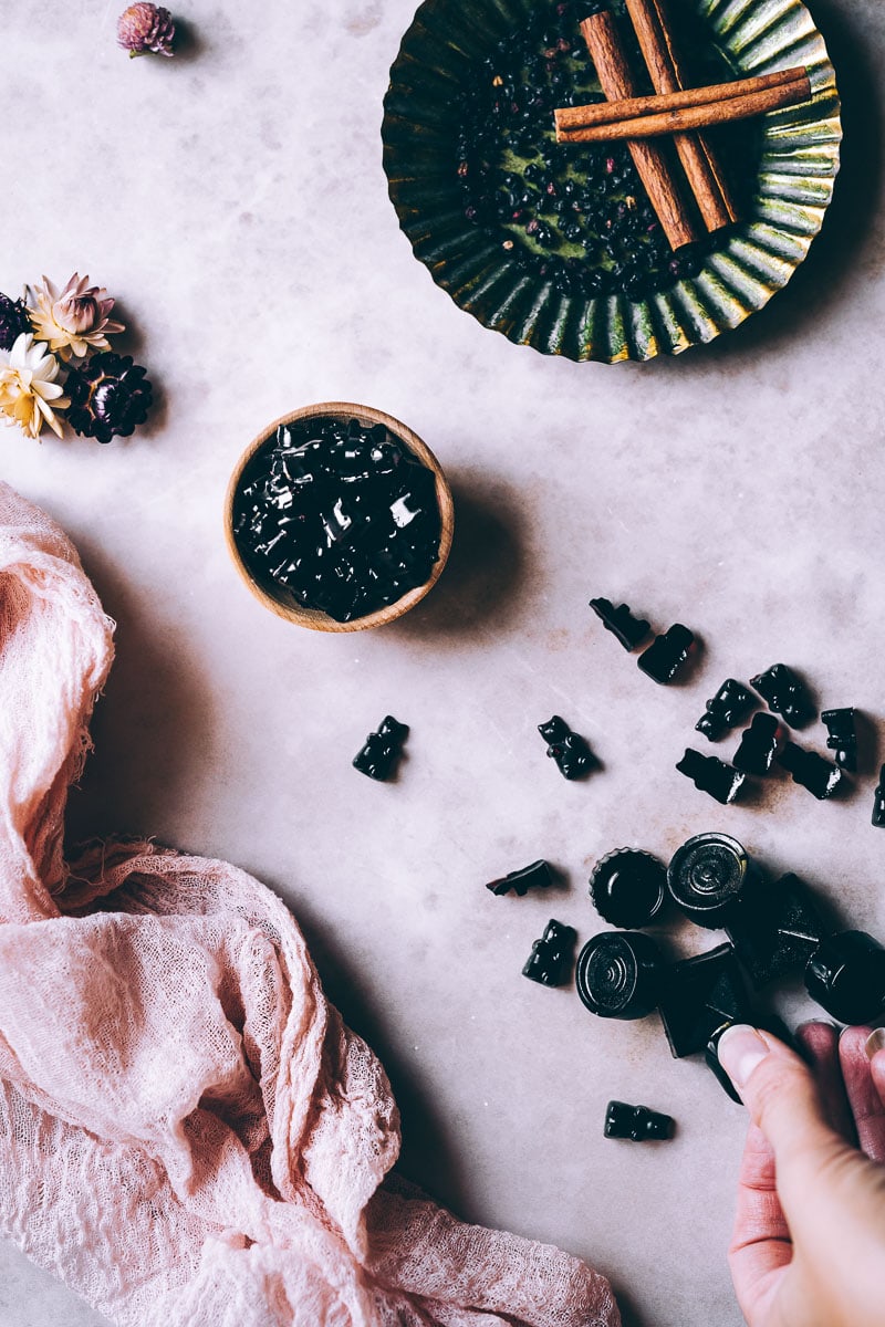 vegan gummy bears with elderberry syrup on a pink backdrop