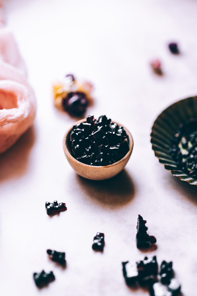 a small wooden bowl filled with elderberry gummies