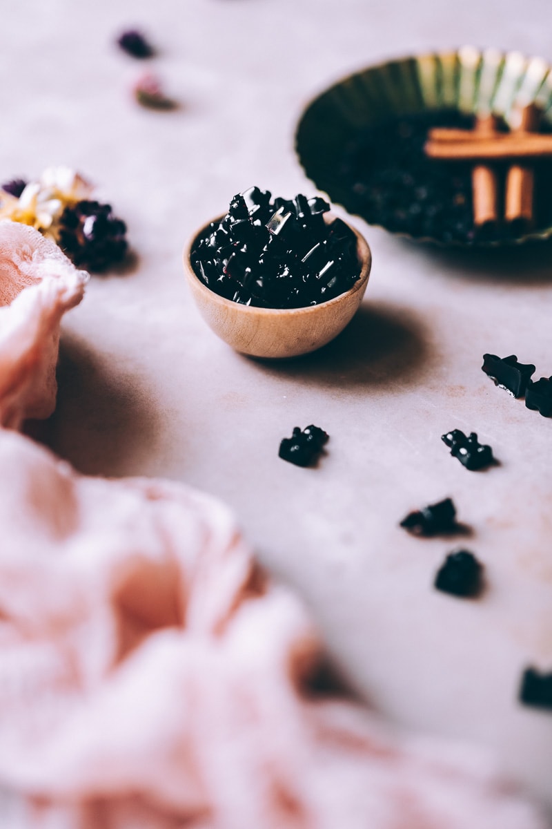 a small light wooden bowl filled with healthy dark purple gummy bears with no gelatin