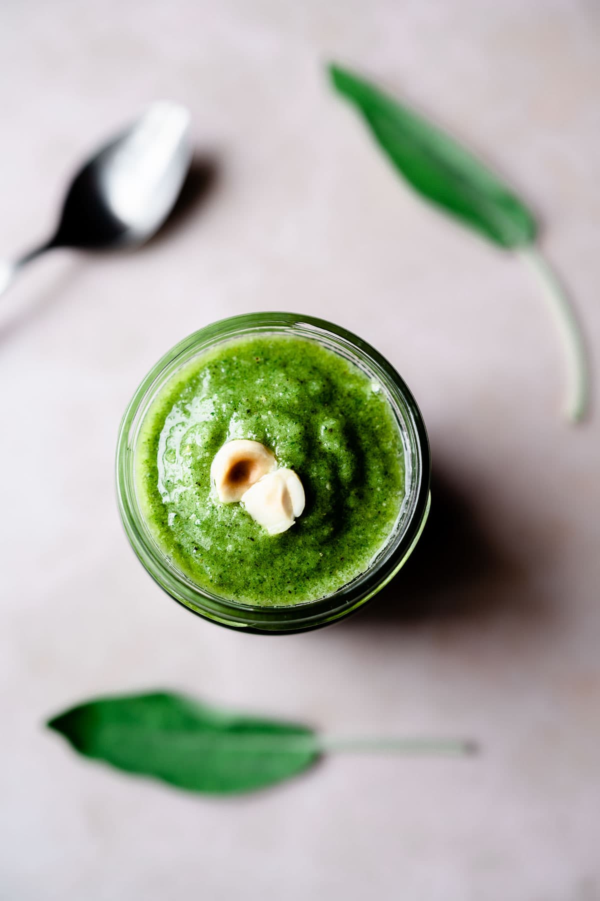 a close up shot of sage pesto in a clear jar