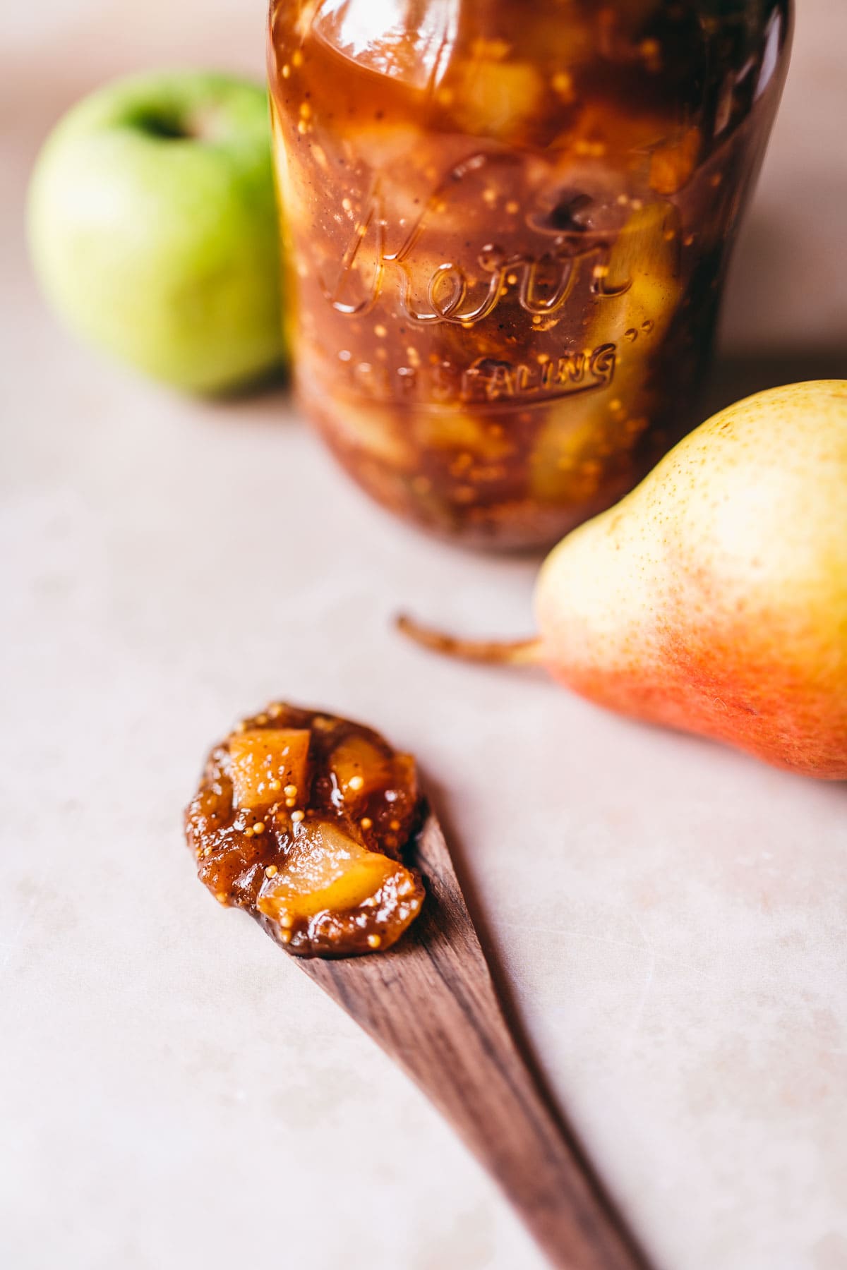 apple pear ginger chutney in a jar and wooden spoon