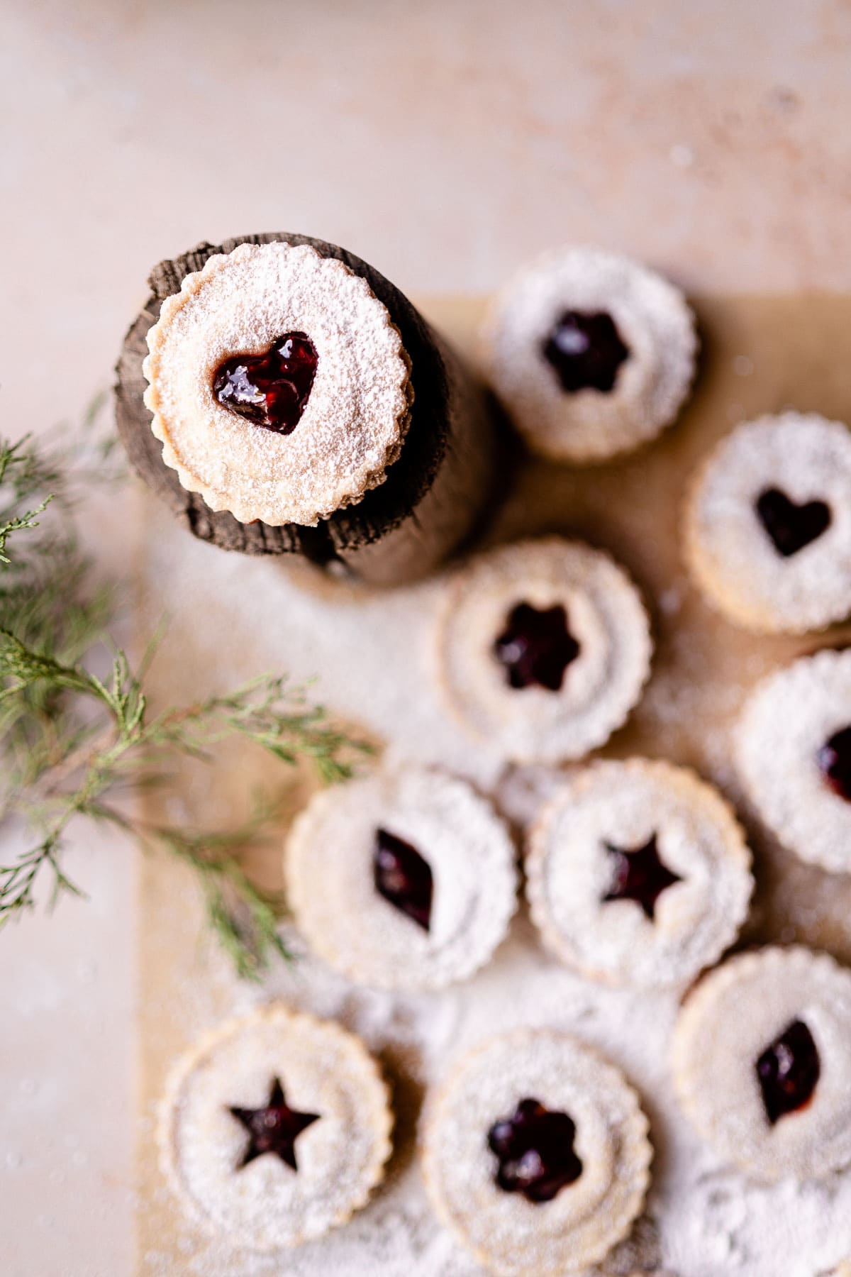 a glute free linzer cookie with a heart shape cut out resting on a wooden log