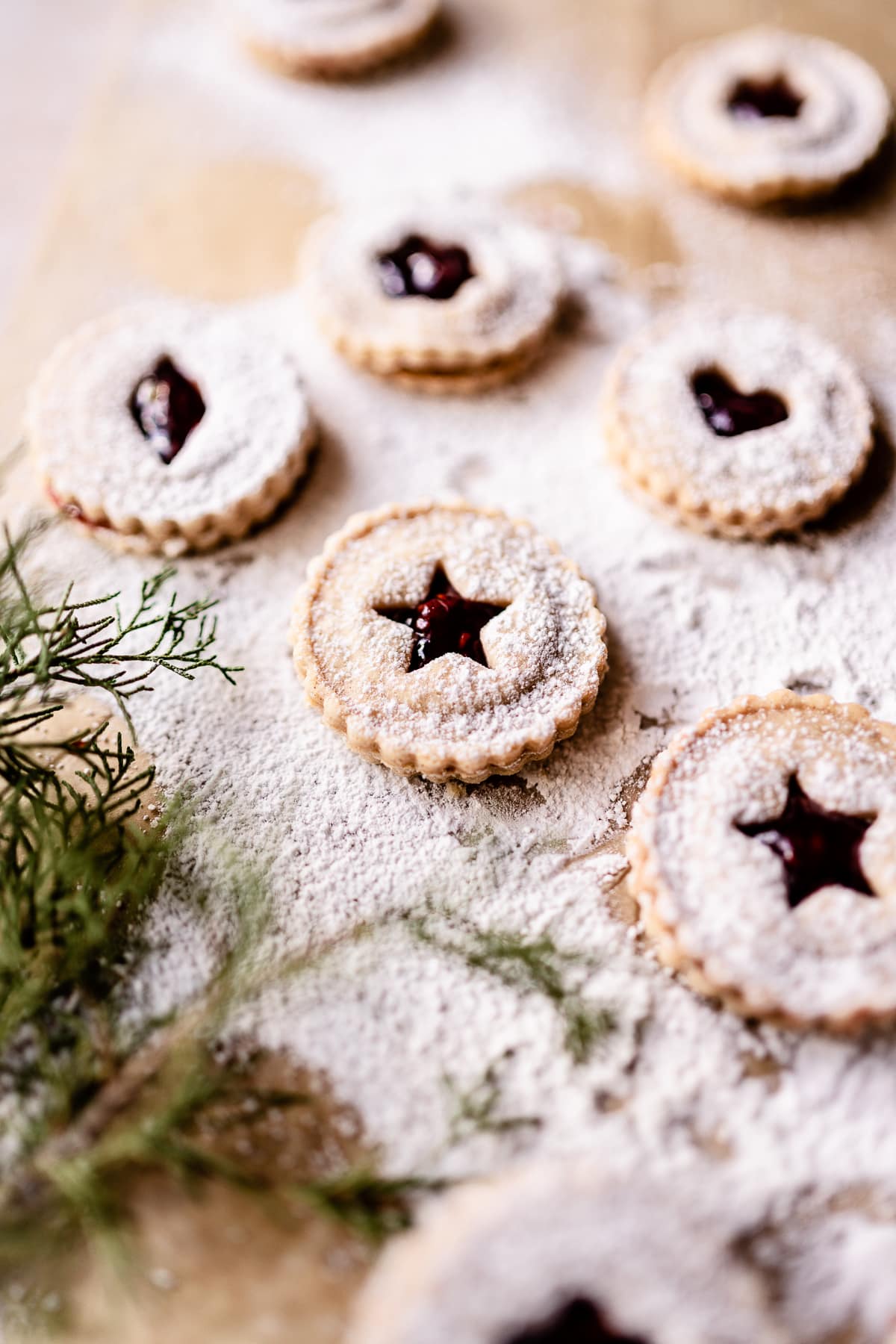 gluten free vegan linzer cookies resting on powdered sugar dusted parchment paper