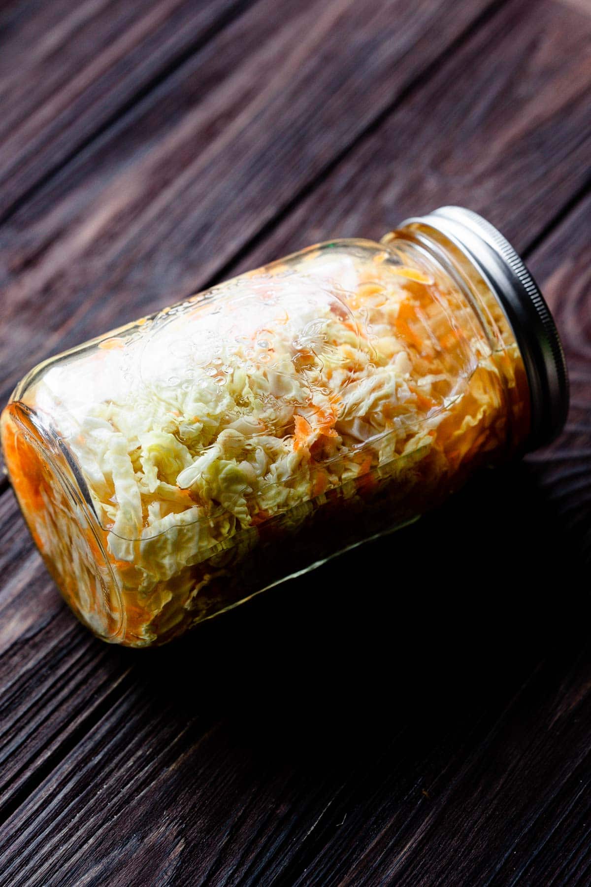a closed mason jar laying on its side, filled with quick pickled cabbage