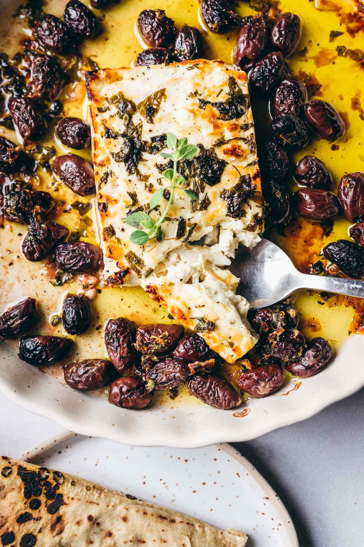 top view of bubbling golden baked feta topped with fresh herbs