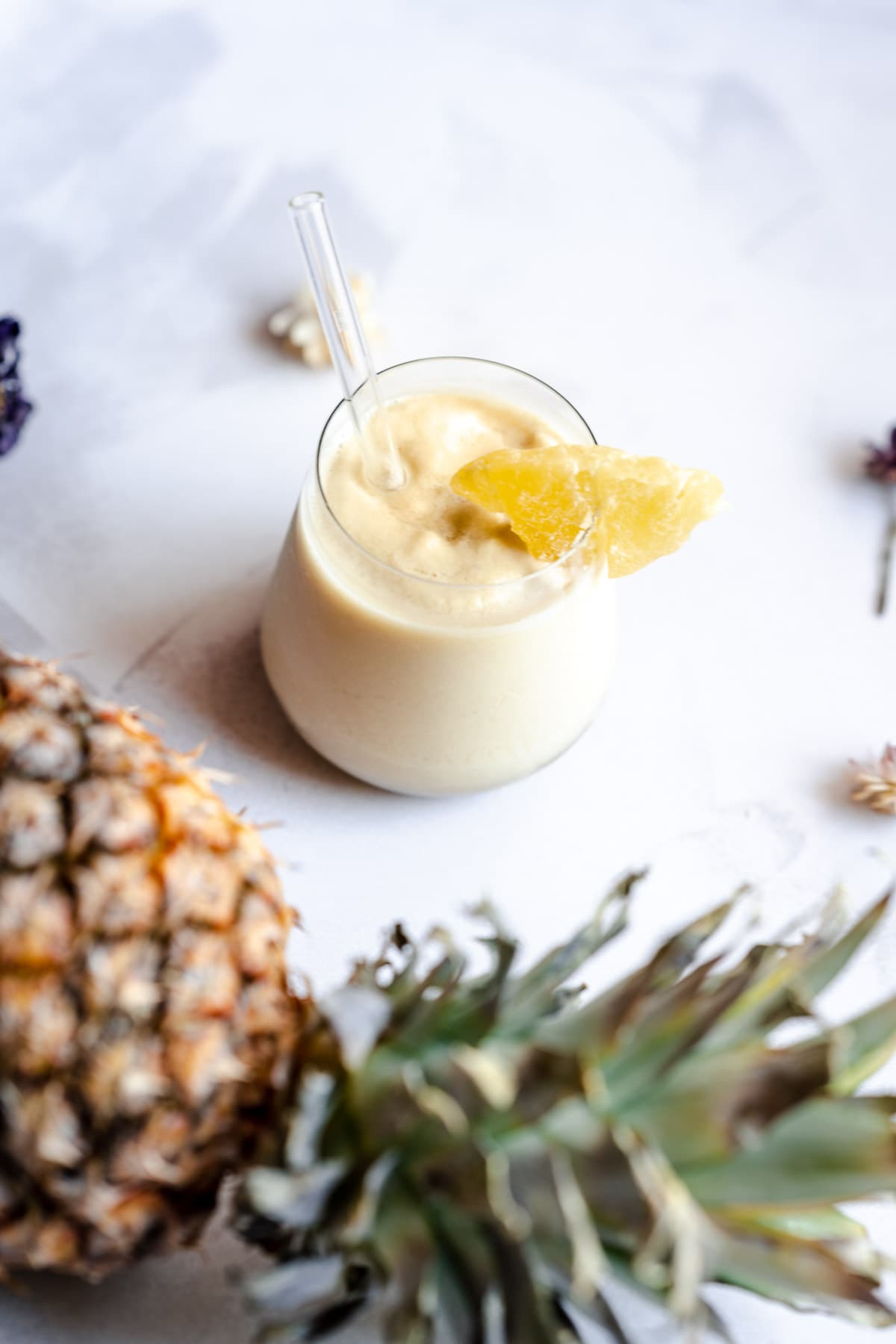 tropical frozen pineapple smoothie in a small glass with a glass 