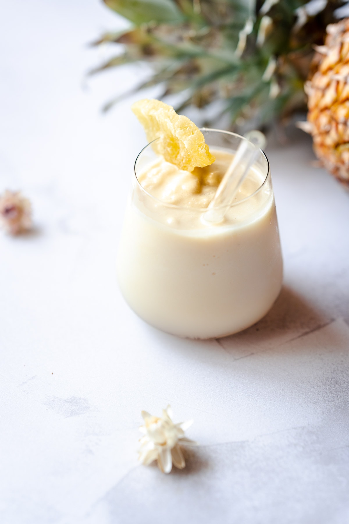 a glass of pineapple smoothie garnished with pineapple