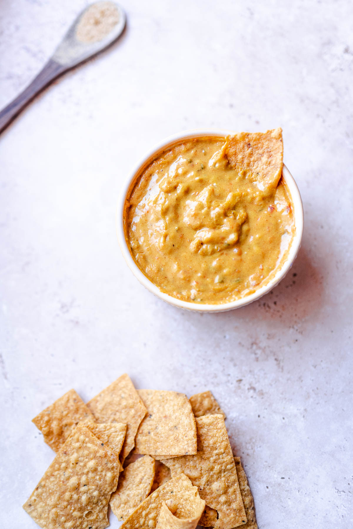 a tortilla chip stuck in an oil free vegan queso dip made with nutritional yeast.