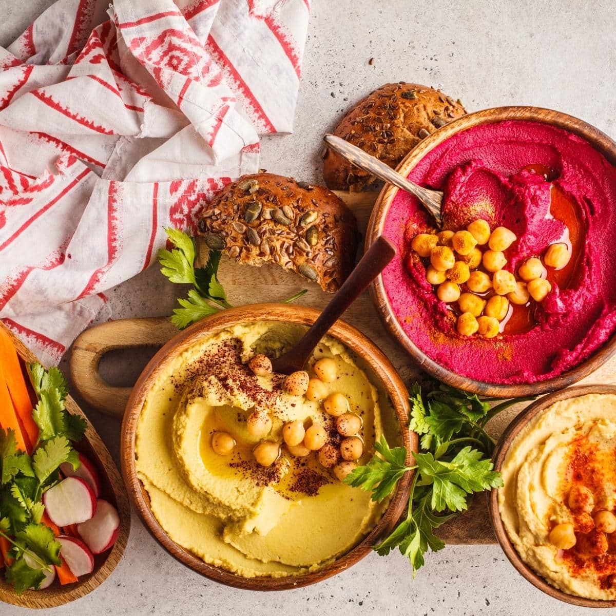 beet hummus, classic hummus and other homemade gluten free hummus varieties in a spread.