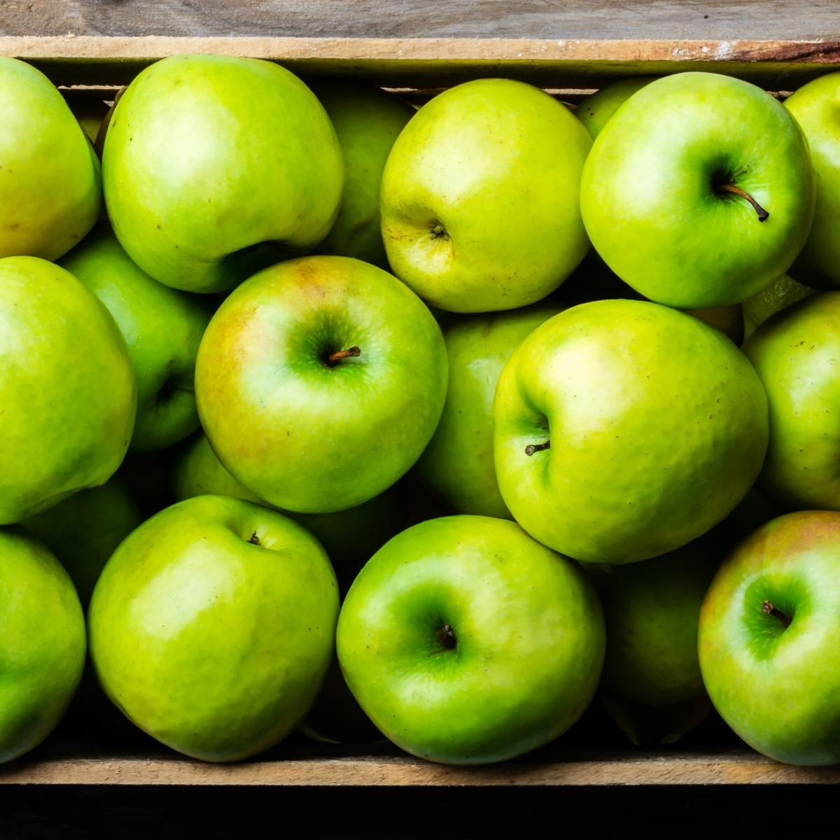 bright green apples in a wooden box.