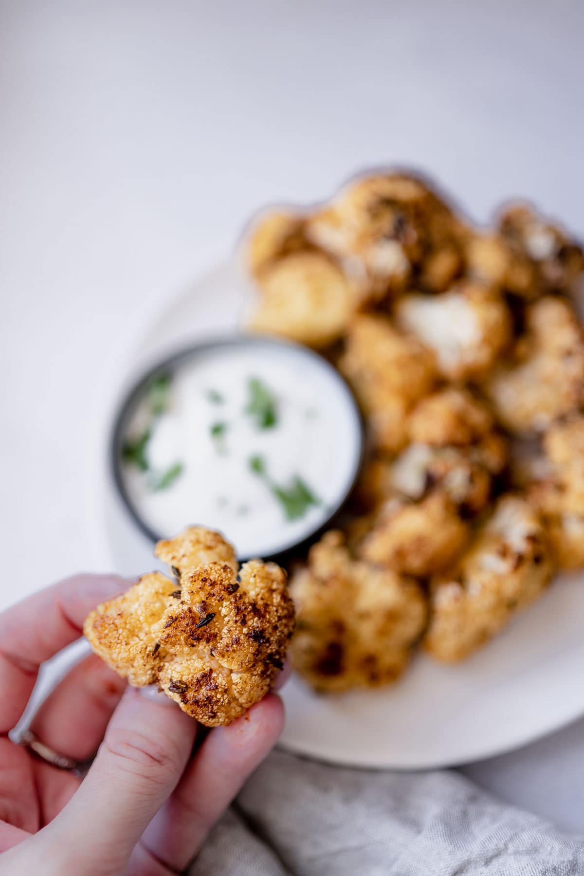 A hand holding an air fry cauliflower floret.