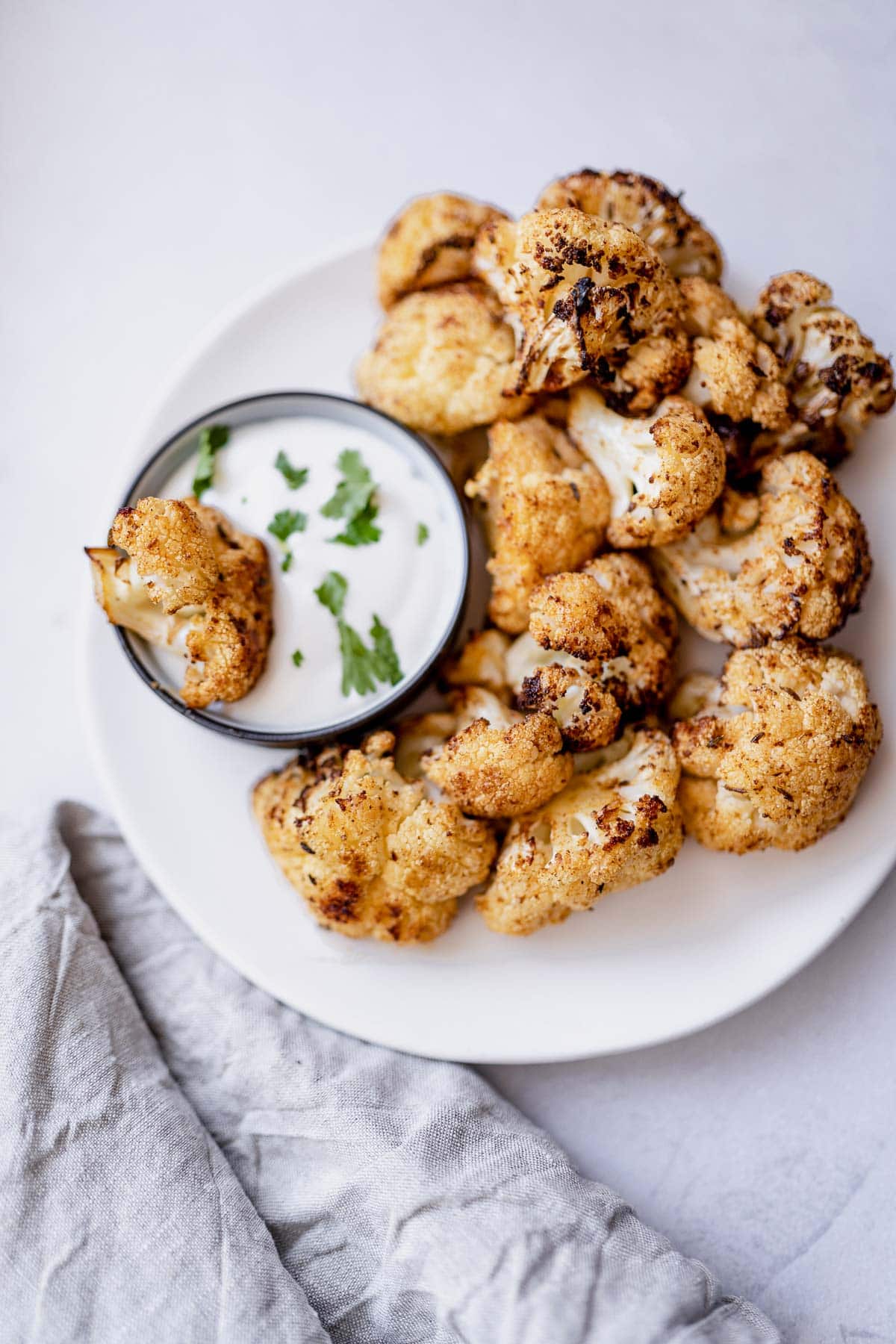 An air fryer cauliflower floret dipped in yogurt.