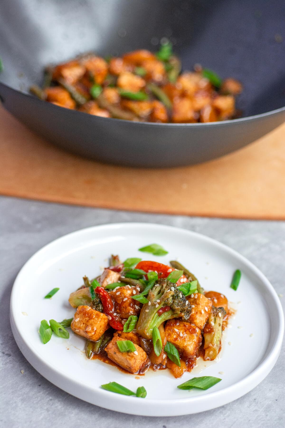 a white plate filled with stir fried veggies and vegan teriyaki tofu