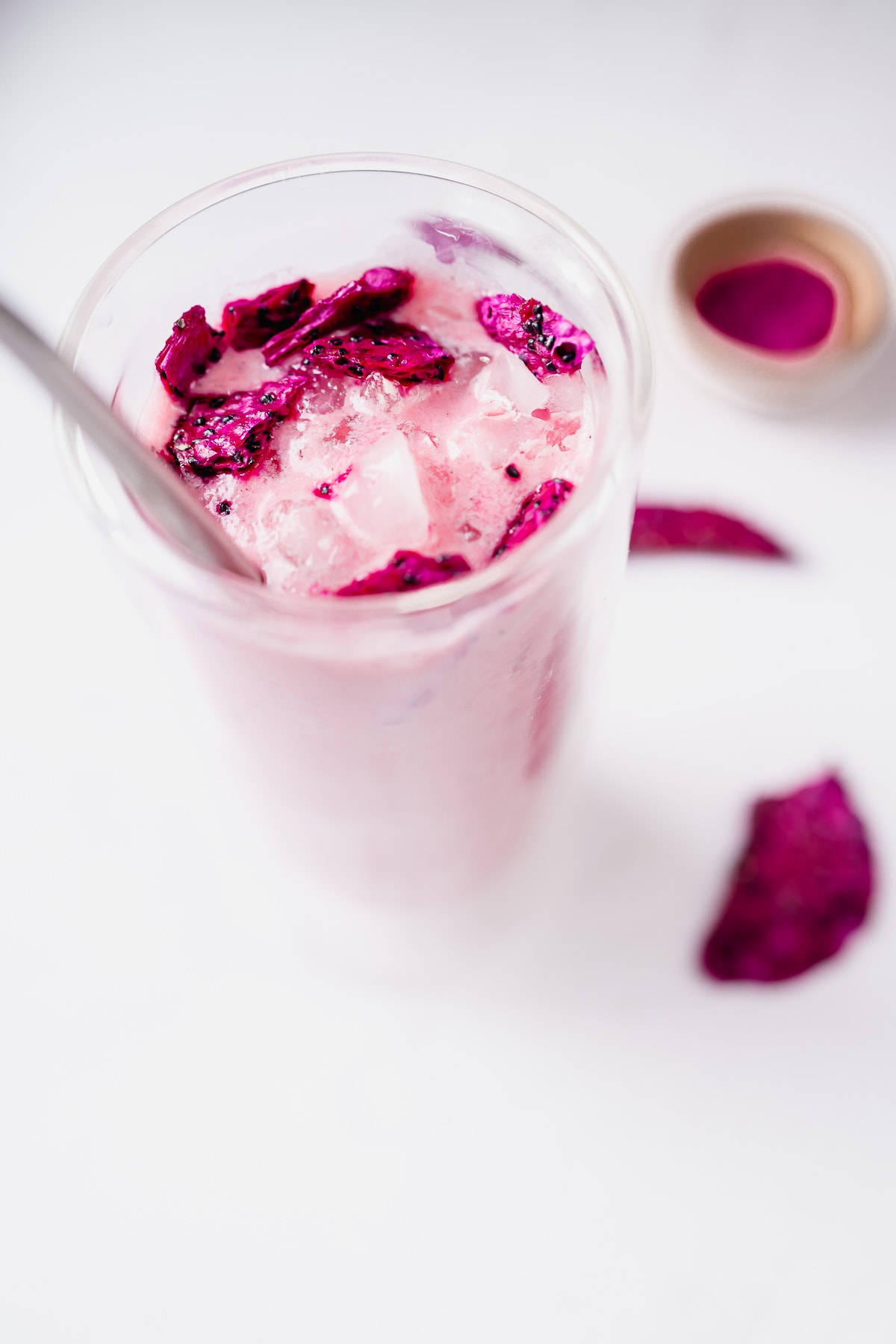 a tall clear glass of copycat starbucks dragon drink with ice and freeze dried dragon fruit.
