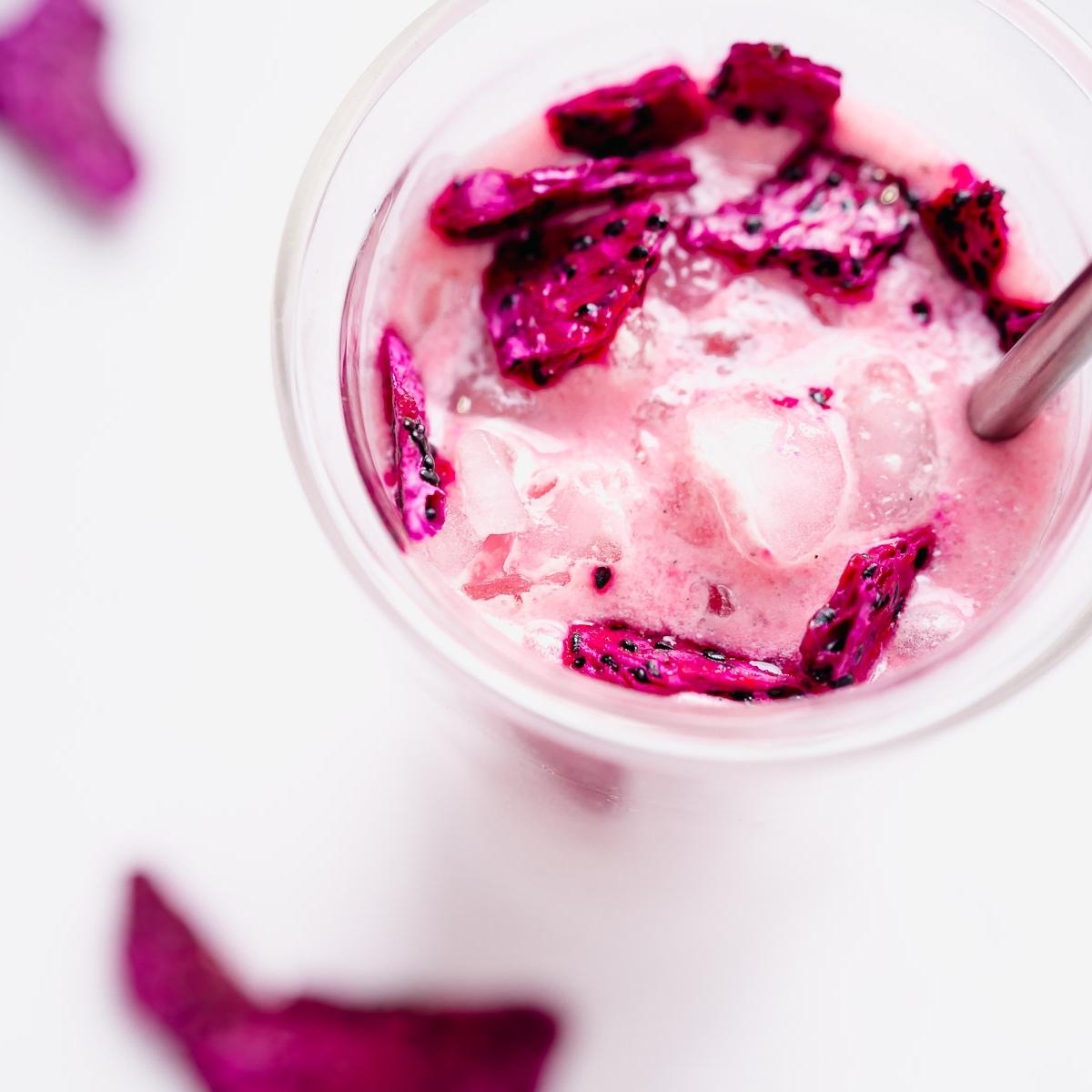 a close up shot of vibrant pink dragon drink with a garnish of dragon fruit pieces floating on top.