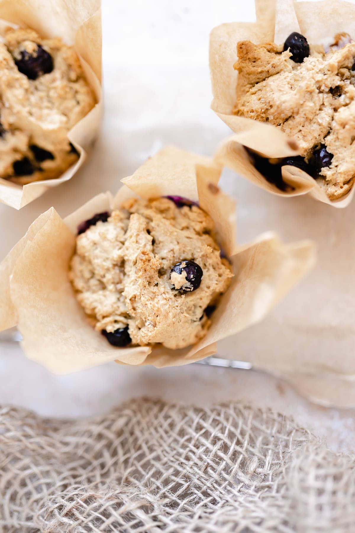 a close up view of a gluten free blueberry muffin wrapped in parchment paper.