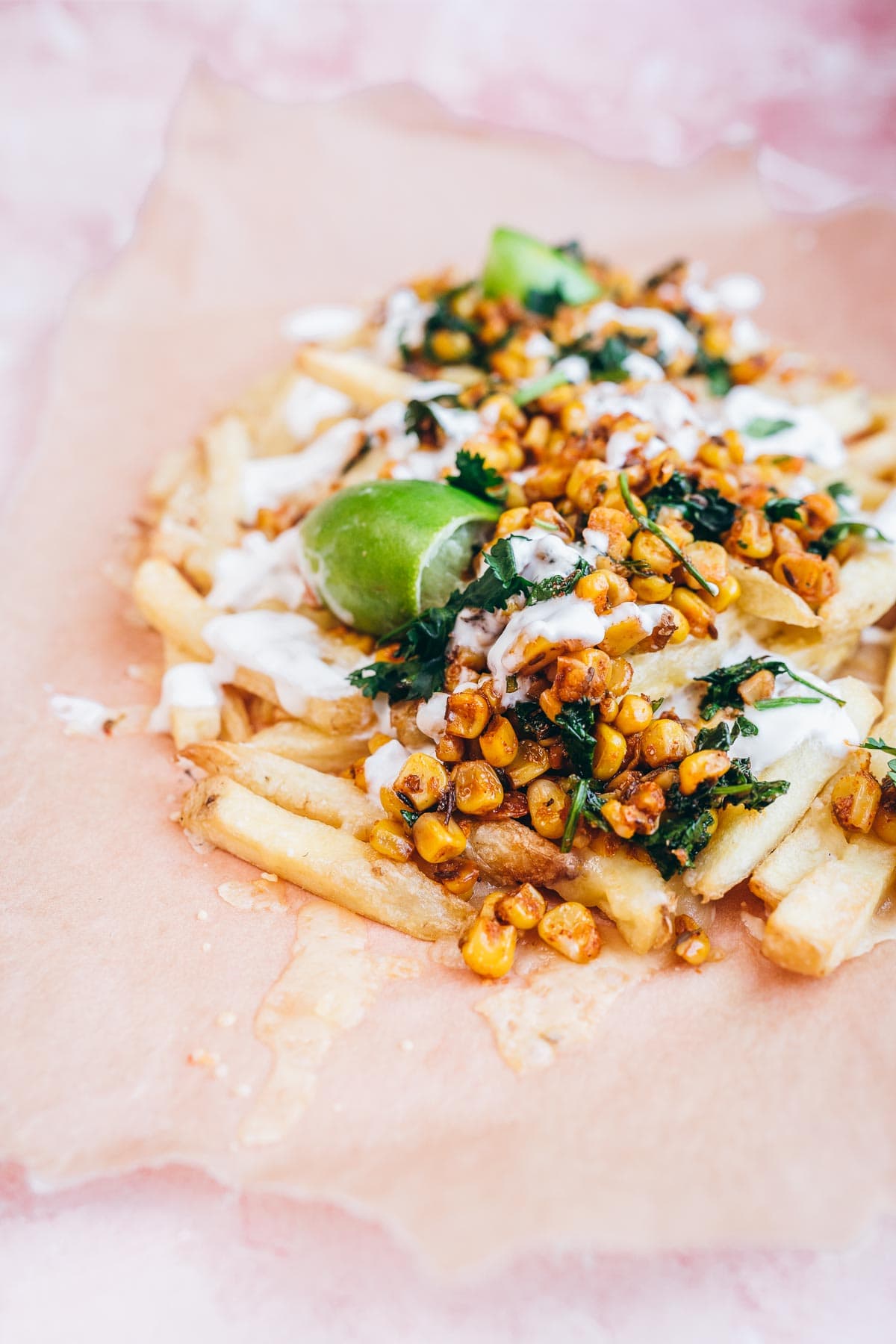 mexican corn fries sprinkled with cilantro and lime juice, resting on brown parchment paper.