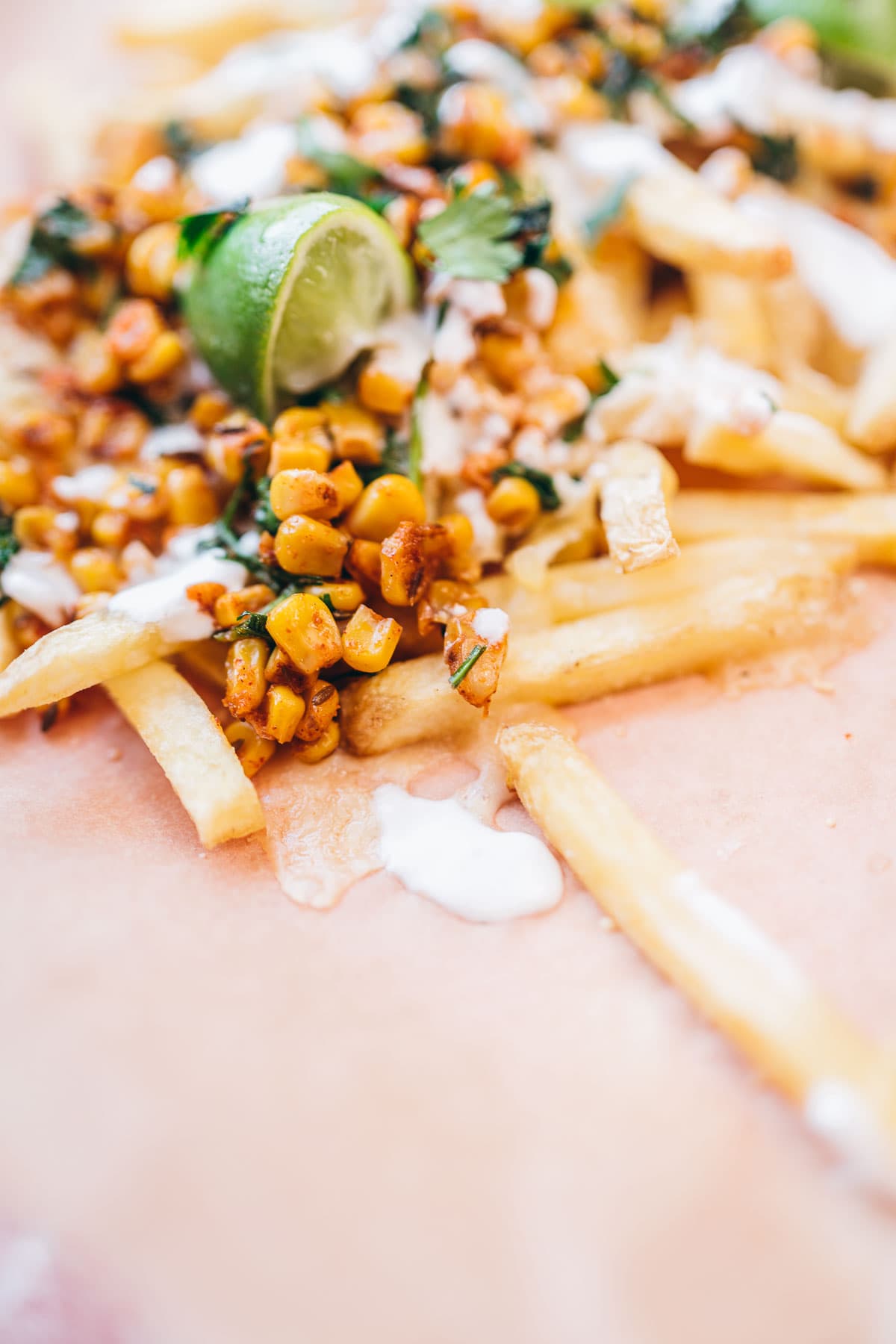 corn fries topped with fresh lime and cilantro resting on brown parchment paper.