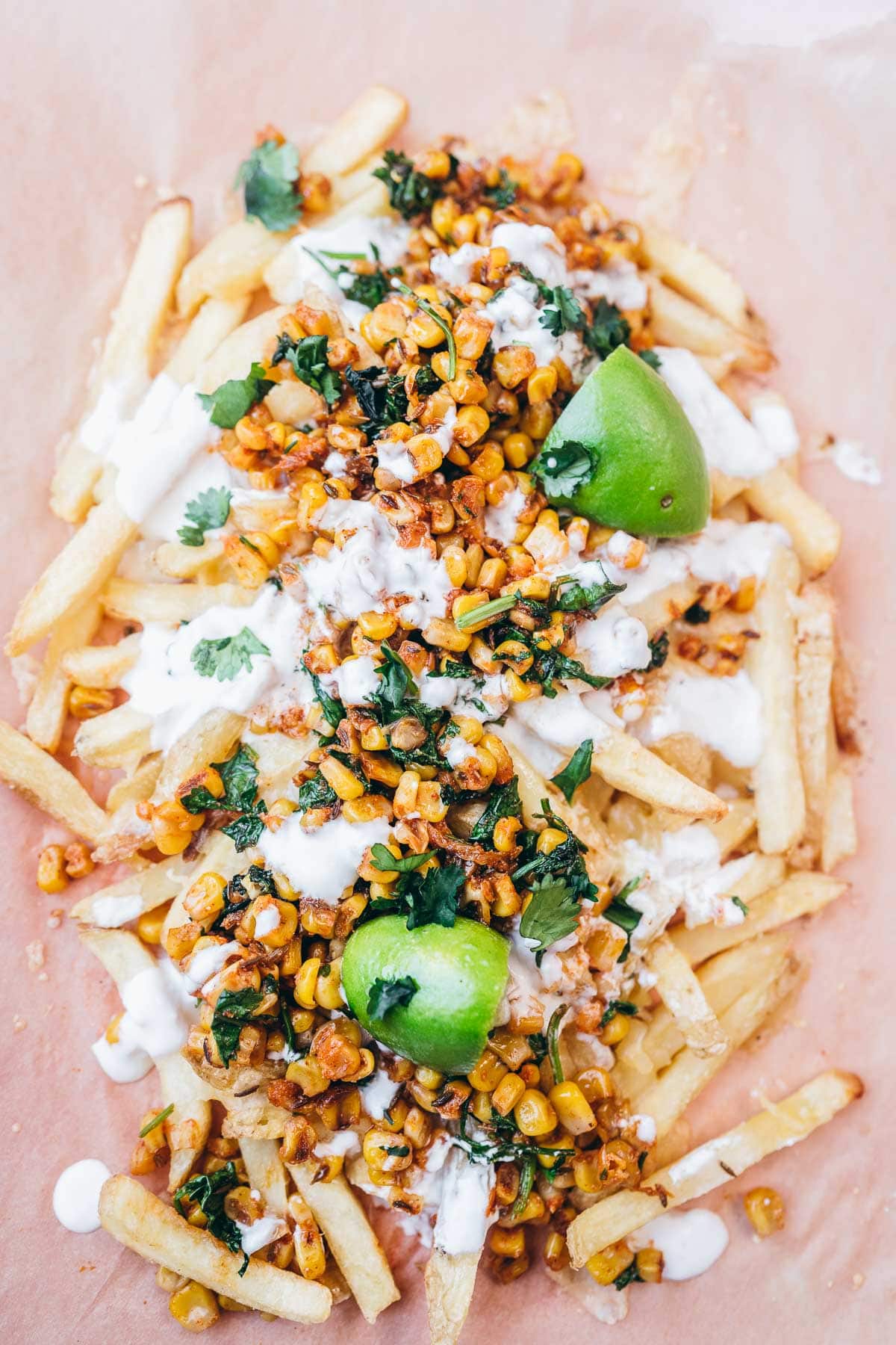 top view of mexican street corn fries with cilantro, lime, mexican crema.