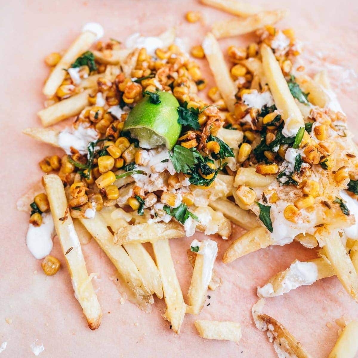 french fries topped with corn, white sauce, cilantro and lime.