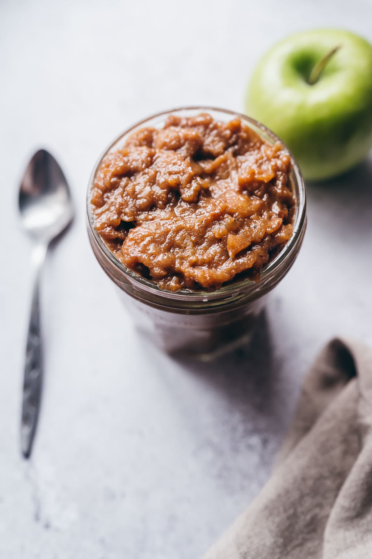 a clear jar of apple curd shining in the light.