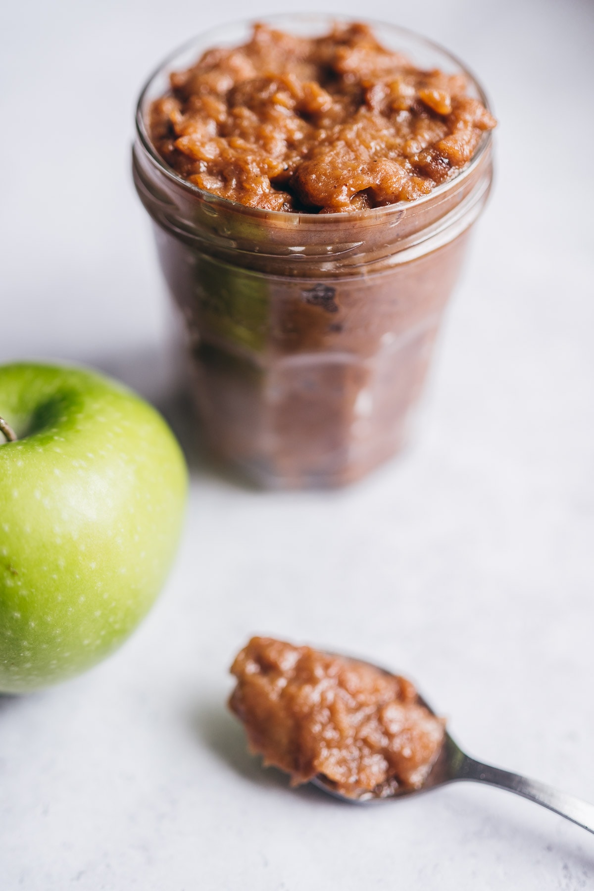 a close side view of a clear jar filled with apple curd recipe.