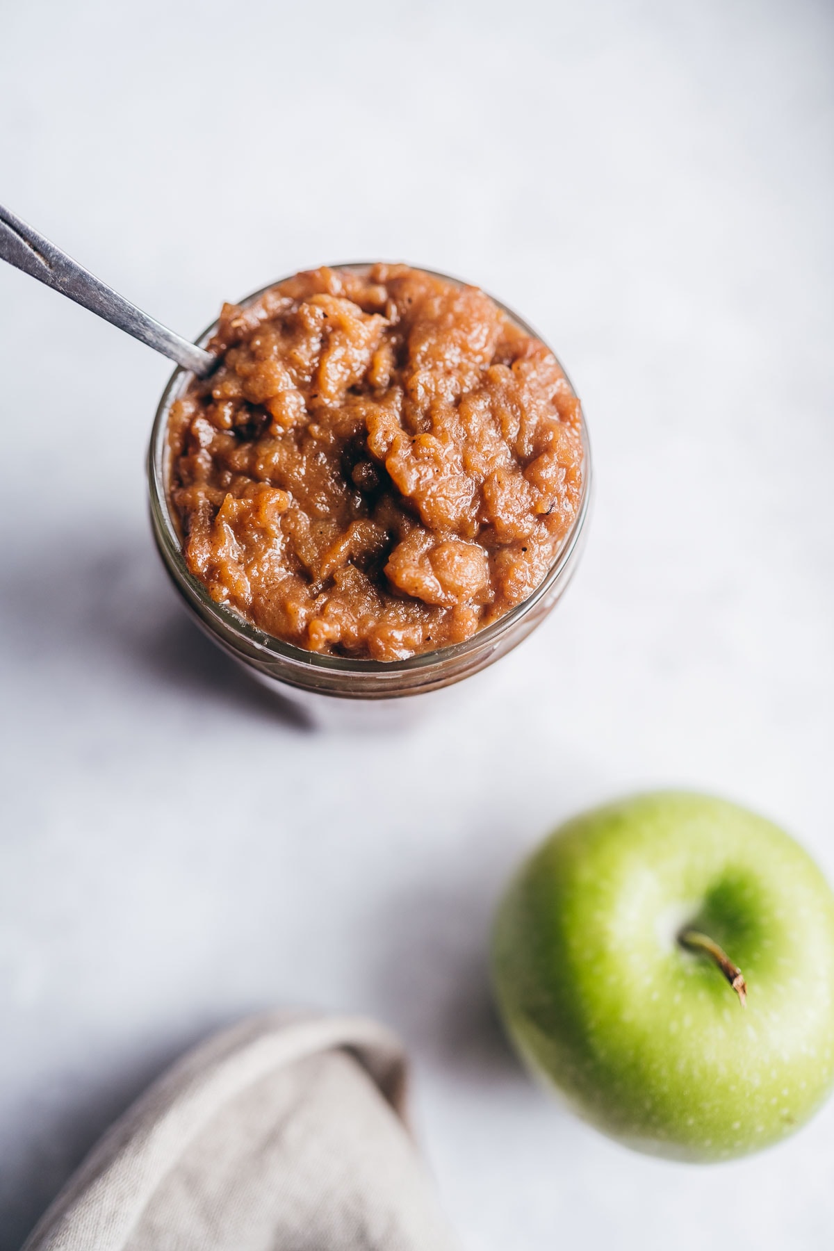 a jar of apple curd next to a bright green apple.