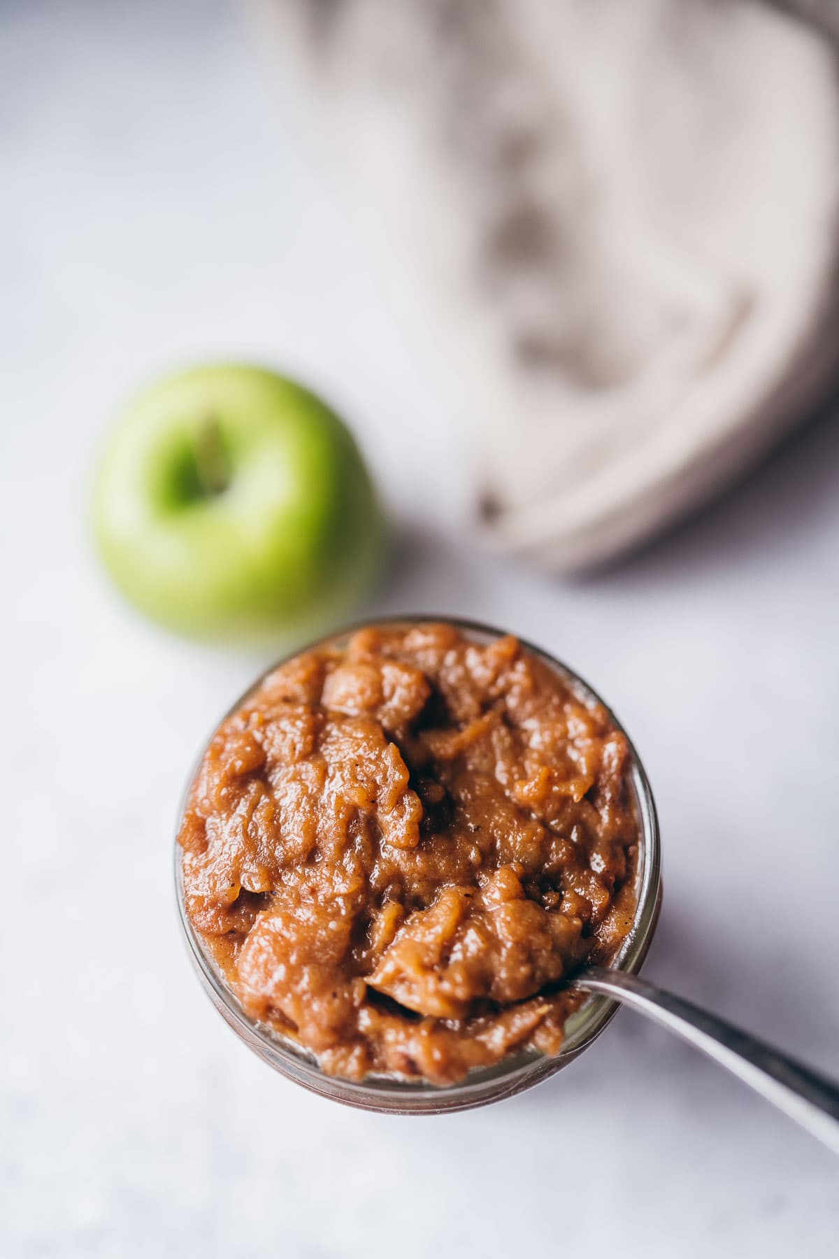 a silver spoon stuck in a jar of homemade apple curd.