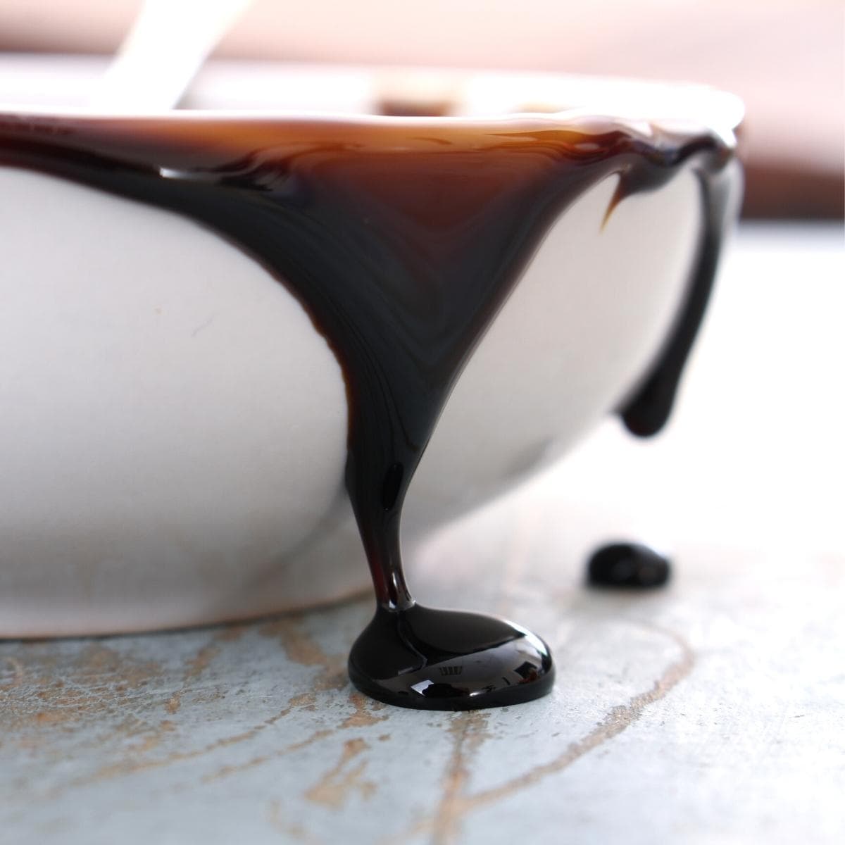 a white ceramic bowl overflowing with molasses.