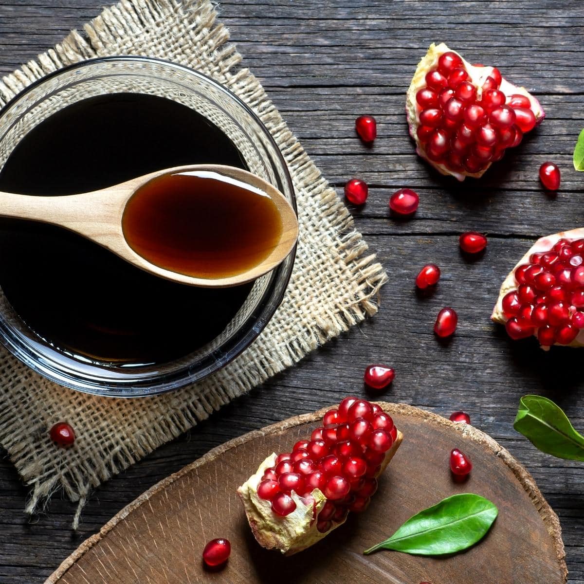 pomegranate molasses resting in a clear bowl on a wooden table.