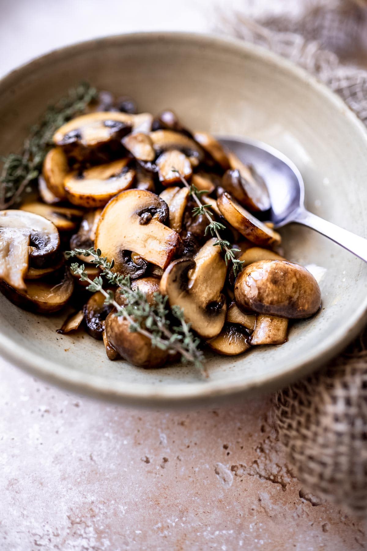 close view of glossy quick sauteed cremini mushrooms topped with fresh thyme.