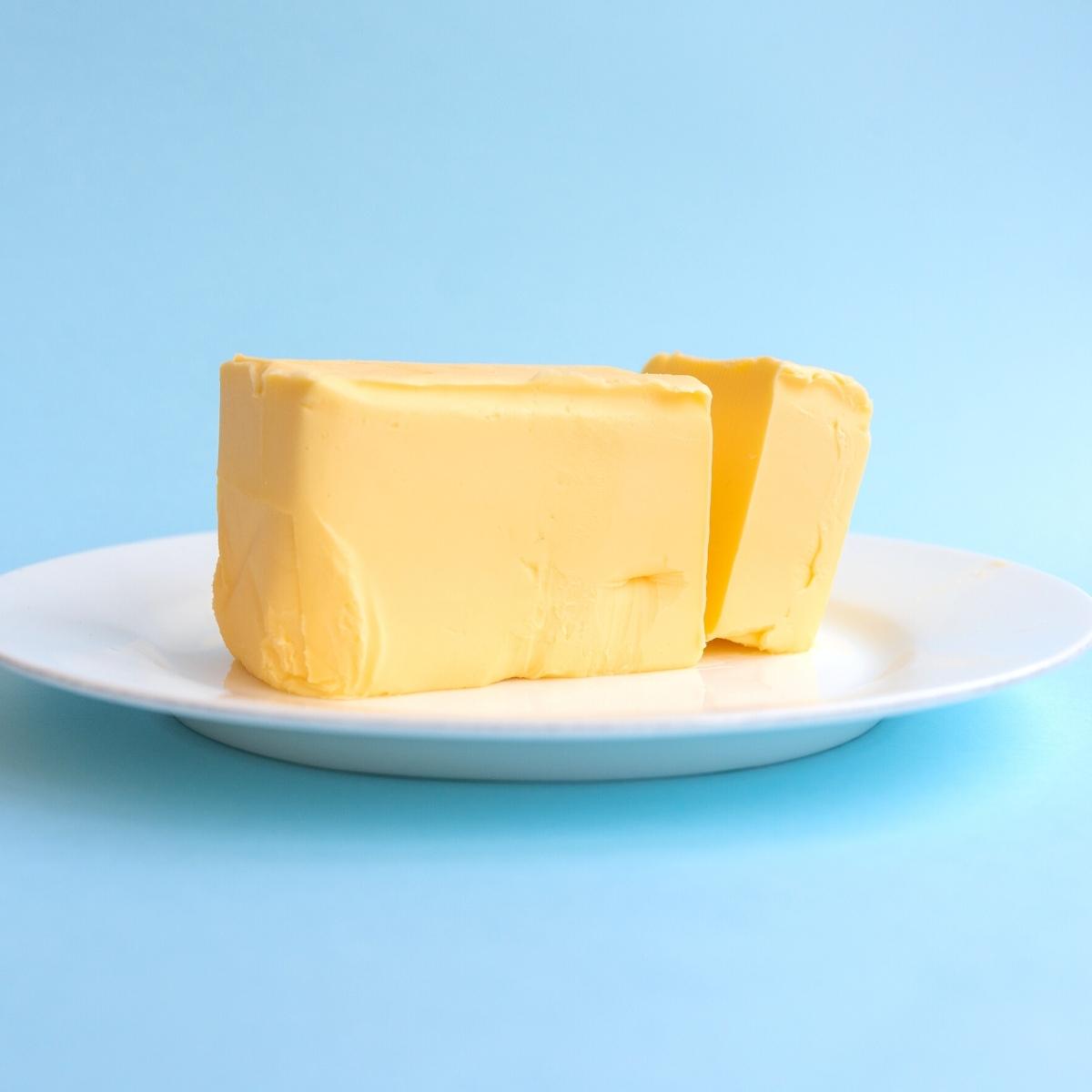 a stack of fresh cream butter on a white plate with a blue background.