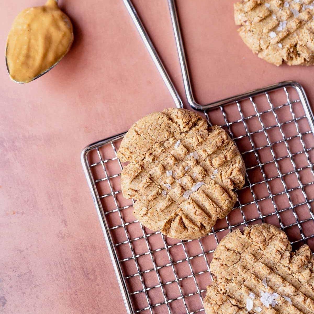 A silver wire rack is topped with tan cookies with a sprinkle of salt and a criss cross pattern.