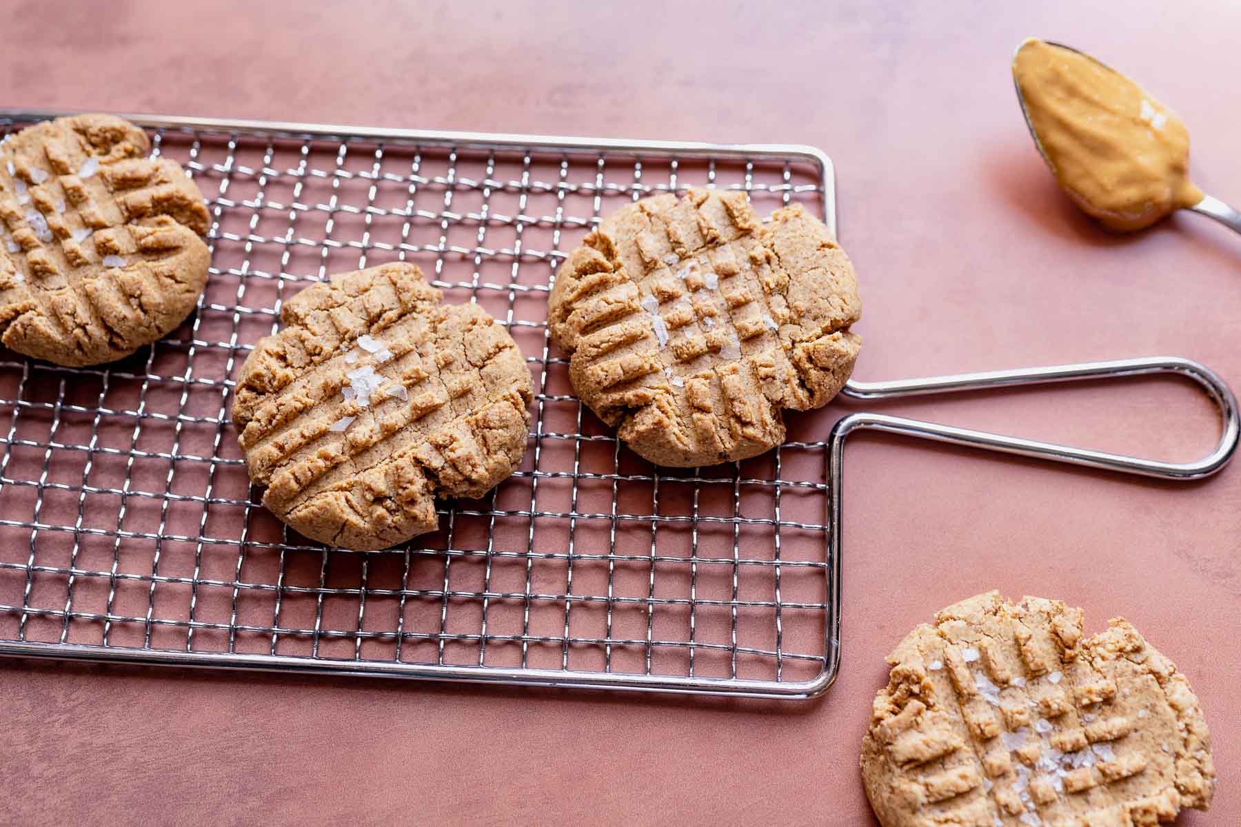 A wire rack with a spread of salted peanut butter cookies resting on top.
