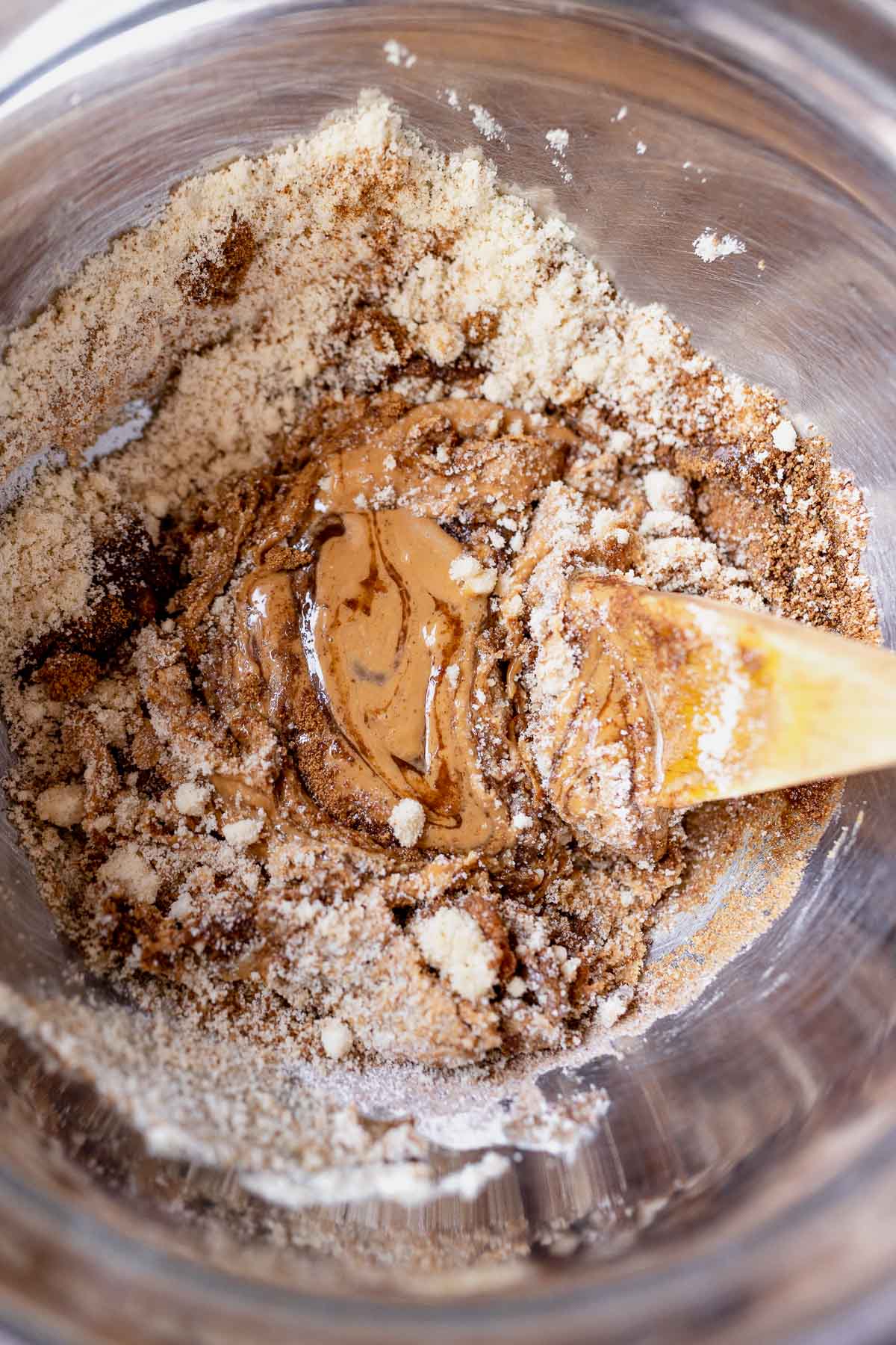 A silver mixing bowl filled with wet and dry baking ingredients.