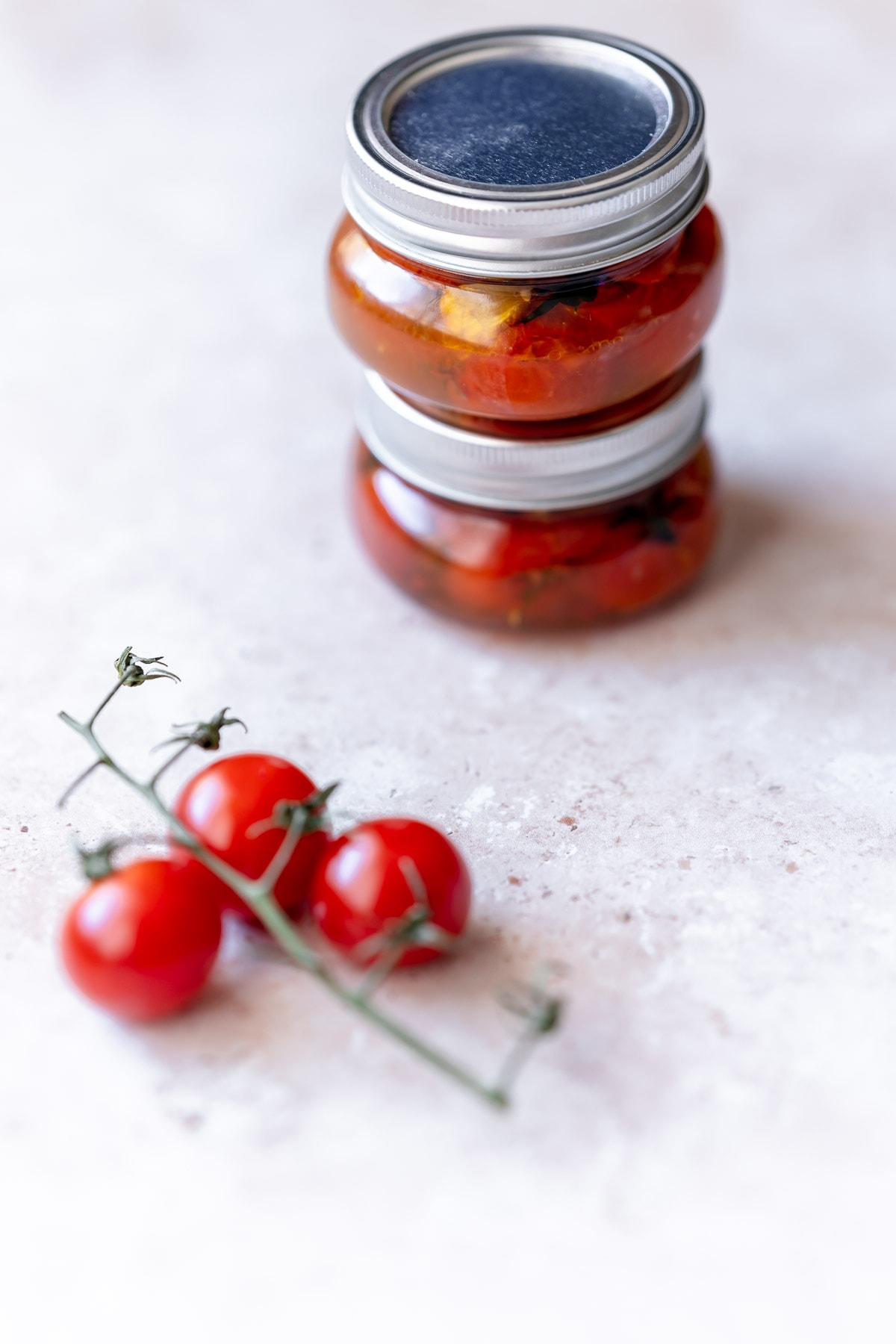 Small stacked jars filled with tomatoes.